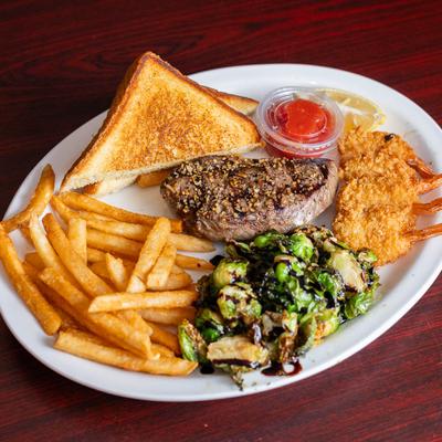 Six ounce steak with fried shrimp, toast, fries and roasted Brussels sprouts.