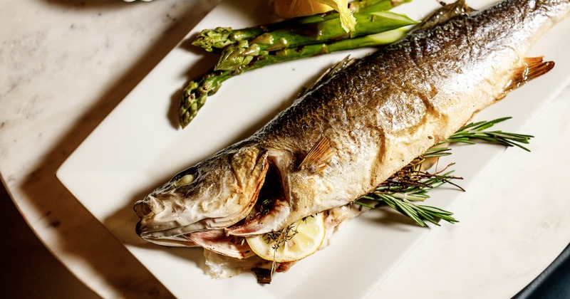 Roasted branzino served alongside asparagus, close up