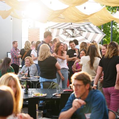 Outdoor social scene with guests mingling at tables during sunset.