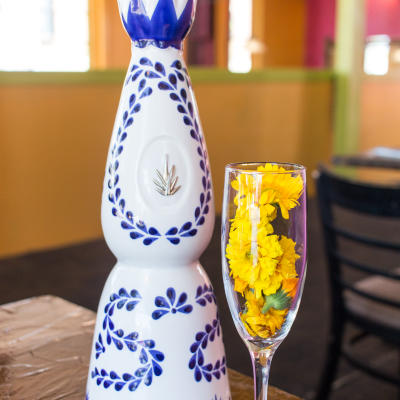 A bottle and a glass with flowers in it.