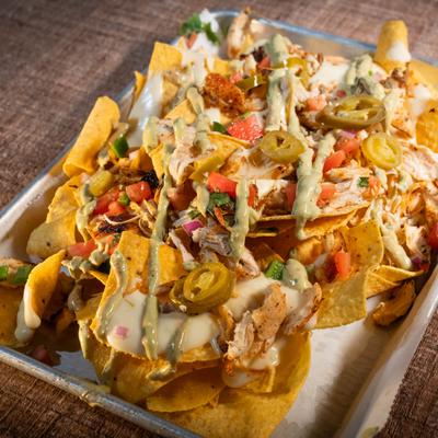 Nachos, with tortilla chips, shredded chicken, cheese, salsa, jalapenos, avocado, and cilantro.
