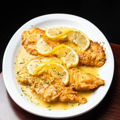 Chicken francese garnished with lemon slices.