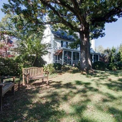 White house with a porch and a shaded front yard.