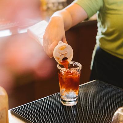 Bartender preparing a cocktail in a salt-rimmed glass.
