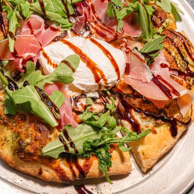 Pizza with prosciutto, arugula and cheese, close up