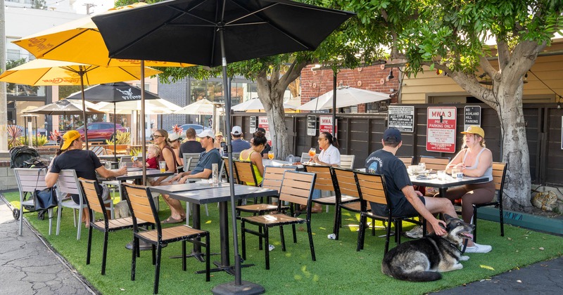 Outdoor dining area with people sitting under umbrellas