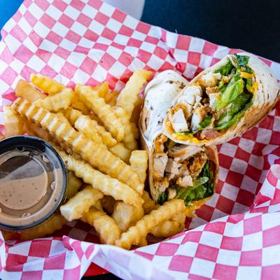 Buffalo Chicken Wrap served in a red basket lined with red-and-white checkered paper.