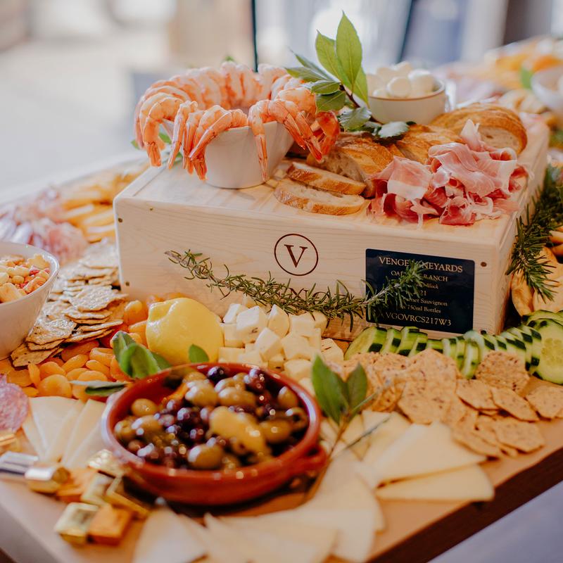 Grazing table with assortment of cheeses, cured meats, fruits, nuts and other items.