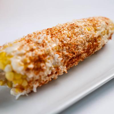 Street corn on a white plate, close up.