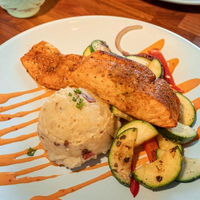 Cajun seasoned baked salmon served with vegetables and mashed potatoes.