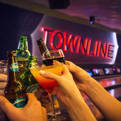 People toast drinks in front of a red Townline sign.