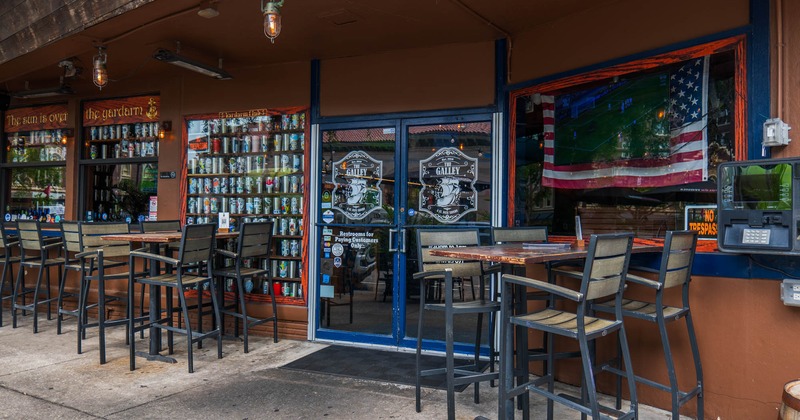 Exterior, restaurant entrance, high tables with chairs, beer cans in the shop window