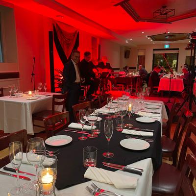 Event setup featuring set candlelit tables and red ambient lighting.