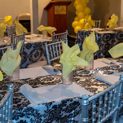 Tables feature black and white damask cloths with yellow napkins.