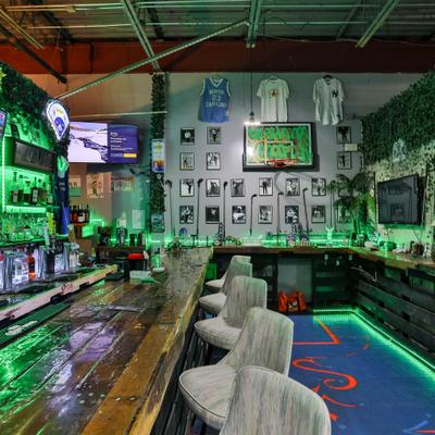 Bar counter with green neon lights and framed pictures.