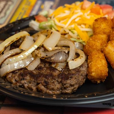 Hamburger steak plate with grilled onions and tater tots.