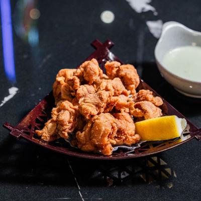 Karaage chicken served with dipping sauce and lemon wedge.