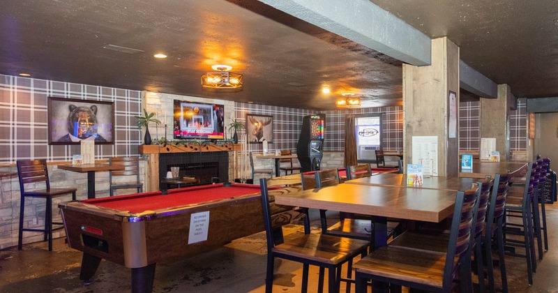 Interior seating area with a pool table, chairs and tables