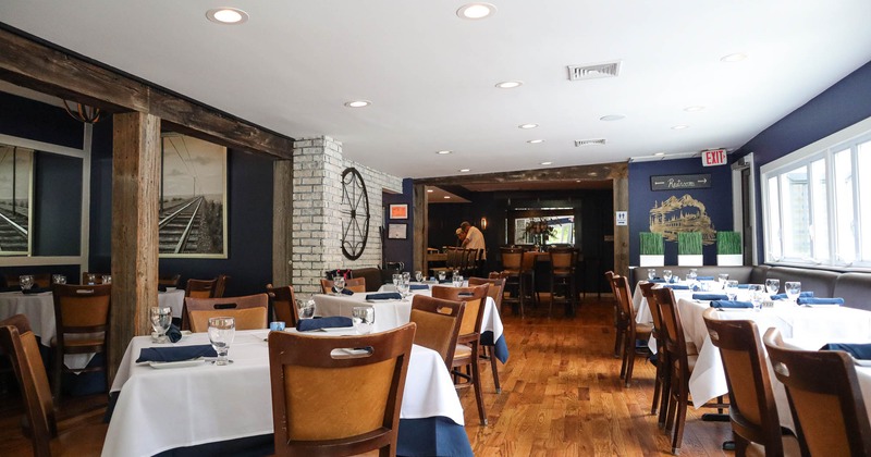 Interior, tables and chairs ready for guests, wooden flooring, windows on the right