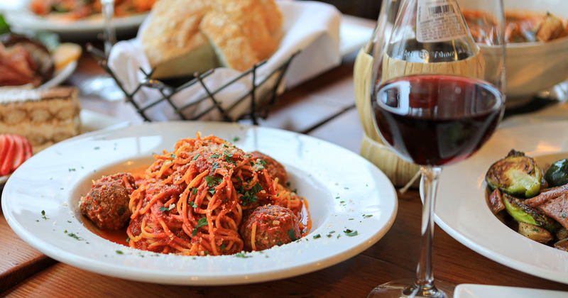Spaghetti and meatballs served with glass of wine