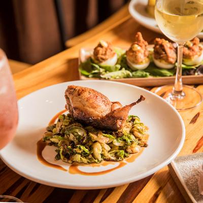 Quail and Brussels sprouts dish on a table with assorted dishes