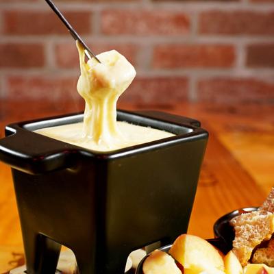 Bread dipped in melted cheese being lifted from a fondue pot.