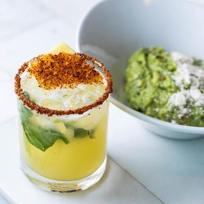 Pineapple mezcal margarita beside a bowl of guacamole.