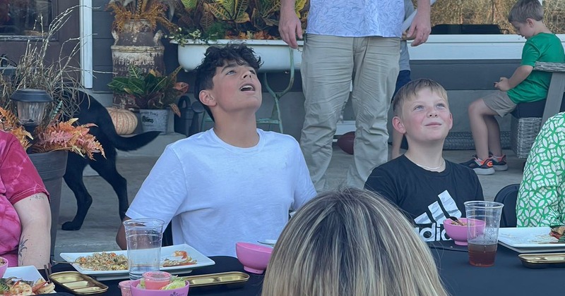 A group of people are enjoying food at a table in an outdoor dining