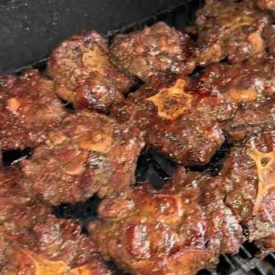 Grilled meat pieces cooking over open flame.