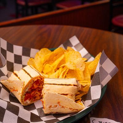 Crispy chicken wrap served with potato chips.