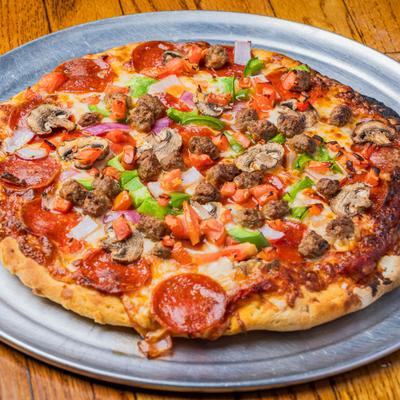 Pizza with bell peppers, tomato, onion, olives, mushrooms, sausage, ground beef, and pepperoni.