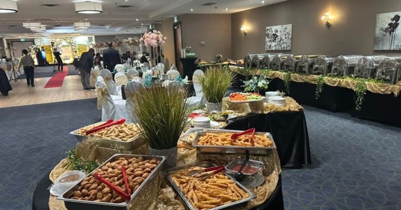 A banquet hall featuring seating area and buffet tables with catering food trays