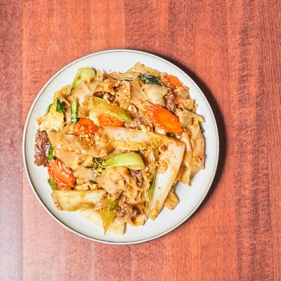 Wok fried rice noodles with soy sauce, beef, carrots, Chinese broccoli, and scrambled eggs.