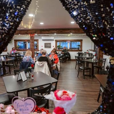 Dining room with wooden ceiling beams, seating area and framed windows.
