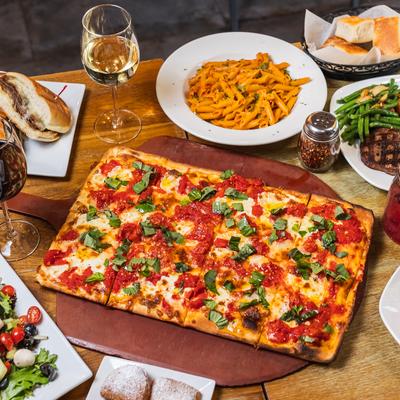 A whole pizza and other meals on the table.