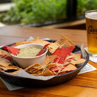 Spinach dip served with tortilla chips and a glass of beer.