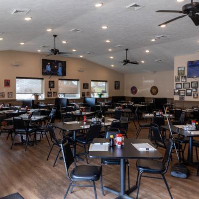 Restaurant seating area with tables. booths, TVs, and ceiling fans.