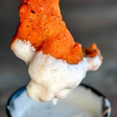 Dipping a wing in a sauce, close up.