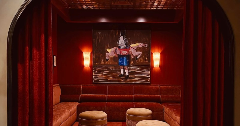 Luxurious red lounge with plush seating, velvet curtains, and a painting
