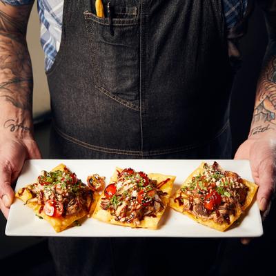 Hands holding the duck confit tostada.