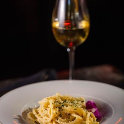Garlic Parmesan Pasta plate, with a glass of white wine in the background
