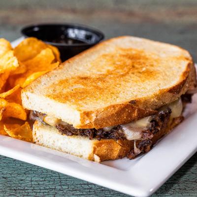 Oxtail Grilled Cheese on toasted sourdough, served with chips.