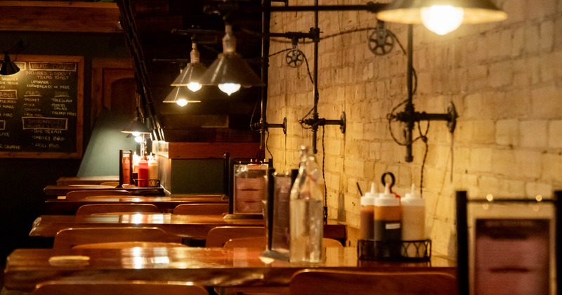 Interior of a cozy restaurant with wooden tables, brick walls, and hanging pendant lights