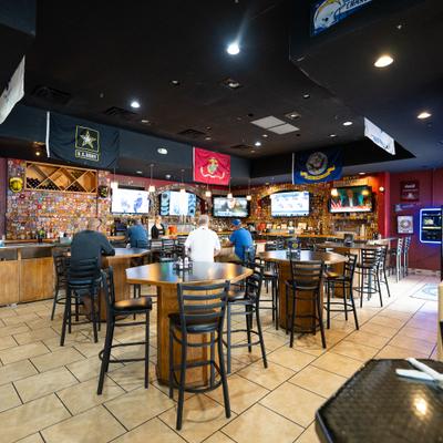 Interior, bar area, stools, tables, bar and tv screens behind.