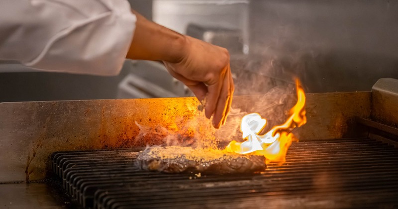 A chef cooking a steak on the grill