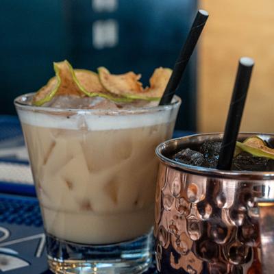 Two cocktail drinks served on a bar counter.