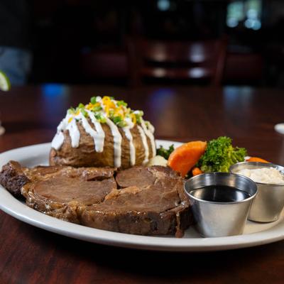 Prime rib eye with condiments, loaded baked potatoes and steamed veggies.