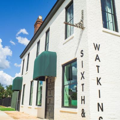 Storefront with white brick facade, green canvas awnings over the entrance and signage.