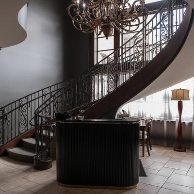 Interior featuring a prominent curved staircase, reception desk and a chandelier.