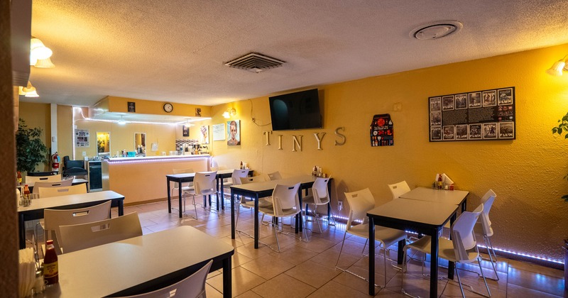 Interior of a warm, cozy restaurant with tables, chairs, and a bar counter